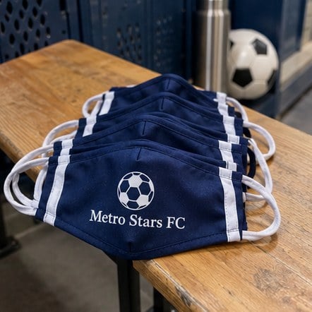 Custom sports team face masks on a locker room bench